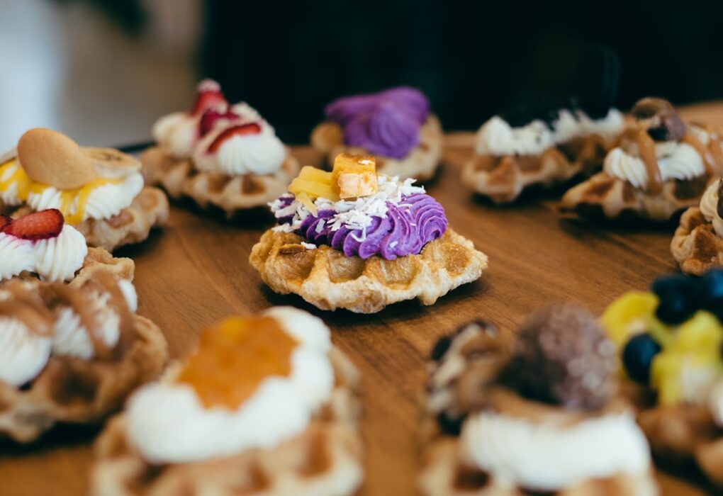 assorted decorative dessert waffles topped with colorful icing and fruit