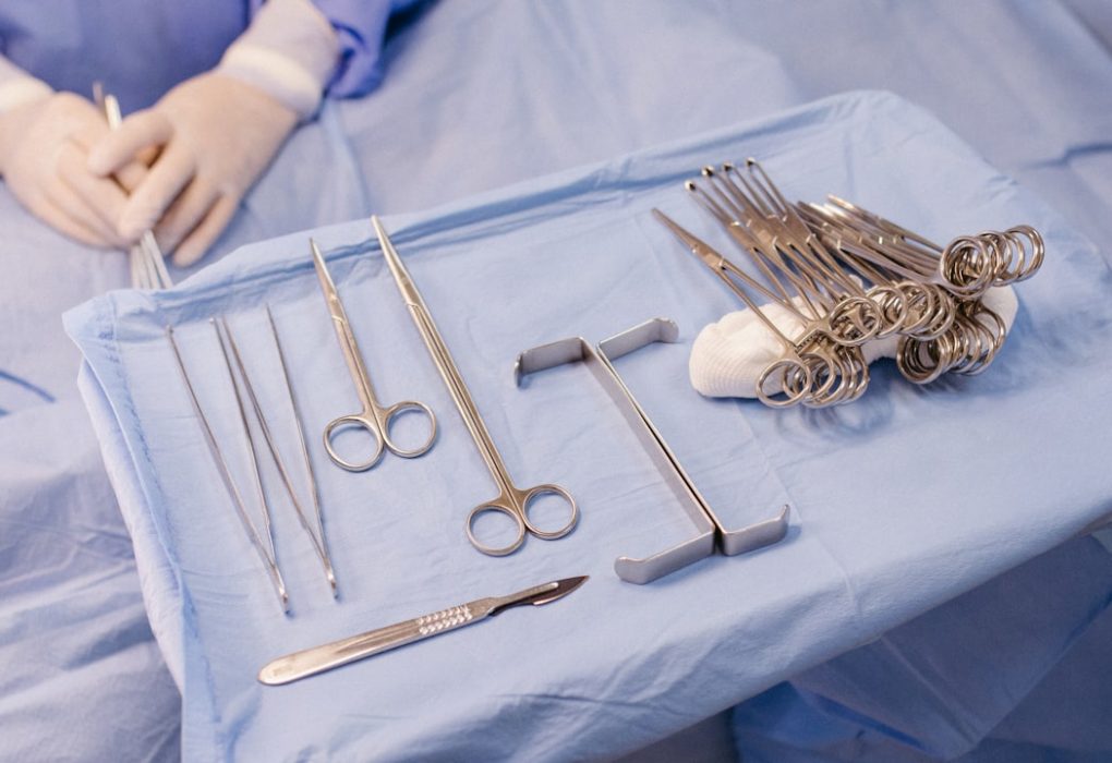 A surgical tray with various surgical instruments laid out on a blue tablecloth.