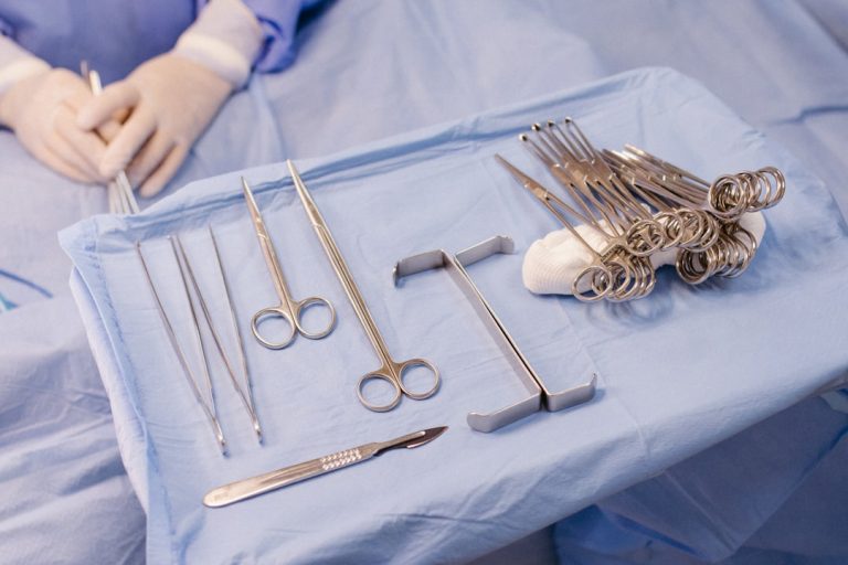A surgical tray with various surgical instruments laid out on a blue tablecloth.