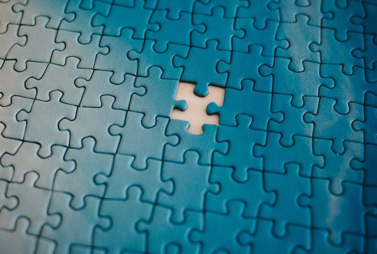 A close-up view of a jigsaw puzzle with a single piece missing in the center, emphasizing the concept of incomplete task